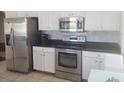 Modern kitchen featuring stainless steel appliances, white cabinets, and stone backsplash at 14845 Huntley Dr, Orlando, FL 32828