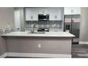 An updated kitchen features white cabinets, stainless steel appliances, and a backsplash at 12020 Villanova Dr # 107, Orlando, FL 32837