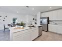 Spacious kitchen with a central island, stainless steel appliances, white cabinets, and seamless integration with dining area at 5629 Gingham Dr, Kissimmee, FL 34758