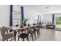 Bright dining area with a wooden table, seating for six, and elegant blue curtains at 5657 Portico Pl, Kissimmee, FL 34758