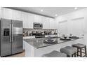 Modern kitchen features a stainless steel refrigerator, microwave, range, and island with seating at 5657 Portico Pl, Kissimmee, FL 34758