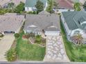 Charming home with a well-manicured lawn, mature landscaping, and a unique patterned driveway at 1709 Latta Ct, The Villages, FL 32162