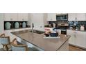 Kitchen island with a sink and gray countertops, complemented by dark tile backsplash and white cabinets at 1899 Clear Sky Dr, Kissimmee, FL 34744