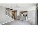 Open-plan living area with stairs, white ceiling fan, access to the kitchen, and neutral colored carpet at 2352 Grand Central Pkwy # 18, Orlando, FL 32839