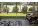 Relaxing screened lanai featuring a cozy armchair, lush backyard view, and tranquil ambiance at 1087 Jackson St, The Villages, FL 32162