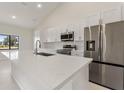 Modern kitchen with stainless steel appliances, white cabinetry, and quartz countertops at 2021 Valencia Dr, Indian Lake Estates, FL 33855
