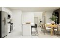 Open-concept kitchen with white cabinets, stainless appliances, island seating, and adjacent dining area at 3019 Totem Rd, Eagle Lake, FL 33839