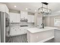 Modern kitchen featuring an island, stainless steel appliances, white cabinetry, and a stylish lighting fixture at 7688 Somersworth Dr, Kissimmee, FL 34747
