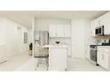Bright white kitchen with stainless steel appliances, center island with bar seating and open layout at 2103 Forage Dr, Kissimmee, FL 34746