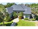 Elegant home with beautiful landscaping, vibrant green lawn, manicured bushes and decorative trees surrounding the entrance at 2660 Wyndsor Oaks Way, Winter Haven, FL 33884
