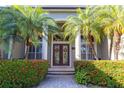 Charming front entrance with beautifully landscaped bushes and palm trees, and glass doors leading to luxury inside at 2660 Wyndsor Oaks Way, Winter Haven, FL 33884