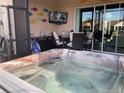 A beautiful hot tub sits on an outdoor screened in patio with comfortable seating and a mounted television at 1415 Colonial Ct, Winter Haven, FL 33884