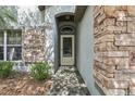 Close up of the front door with brick accents and stone cladding at 30653 Pga Dr, Sorrento, FL 32776