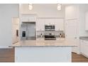 Kitchen featuring granite countertops, stainless steel appliances, white cabinetry, and hardwood flooring at 14404 Sw 19Th Pl, Ocala, FL 34481