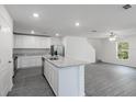 Modern kitchen featuring a center island, gray wood floors, stainless appliances, and a staircase at 587 Bay Leaf Dr, Poinciana, FL 34759