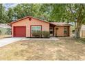 Charming single-story home with a well-maintained lawn and a red garage door at 1313 Periwinkle Ct, Lakeland, FL 33811