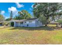 Spacious yard surrounds a light-blue home featuring mature trees and a well-maintained lawn at 3360 Cross Fox Dr, Mulberry, FL 33860