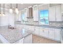 Modern kitchen boasts white cabinetry, granite countertops, mosaic backsplash, and stainless steel range hood at 23 Marden Dr # 51, Ormond Beach, FL 32176