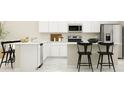 Bright kitchen with white cabinets, an island with bar seating, and stainless steel appliances at 2341 White Buffalo St, Apopka, FL 32703