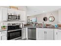 Modern kitchen features stainless steel appliances, gray countertops and cabinetry with an open concept design to the living room at 3282 Armstrong Ave, Clermont, FL 34714