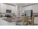 Modern kitchen featuring white cabinetry, stainless steel appliances, and a center island with barstool seating at 5611 Vinyasa Rd, Clermont, FL 34714