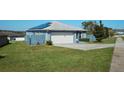 Side view of a blue single-story home with solar panels and a well-maintained lawn at 612 Chicago Way, Dundee, FL 33838