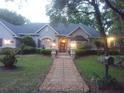 Dusk view of home with manicured lawn, brick path, landscape lighting, and mature trees at 19811 Lake Dorr Rd, Altoona, FL 32702