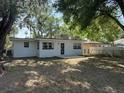 A backyard features a concrete porch and a white home under the shade of leafy trees at 635 Mccormick St, Daytona Beach, FL 32114