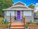 Inviting front porch with wooden decking, planter boxes, a purple front door, and a wreath at 70 N Oak Ave, Umatilla, FL 32784