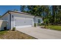 Exterior side view of a home with a two-car garage, and manicured landscaping at 8007 Sw 135Th Loop, Ocala, FL 34473