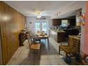 Dining area with wood paneling, tiled floor, adjacent kitchen access, and natural light through french doors at 401 Pine Dr, Sanford, FL 32773
