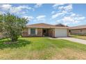 Well-maintained brick home with an attached garage and green lawn under a sunny sky at 492 Caribbean Dr, Lakeland, FL 33803