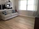 Bright living room featuring modern light gray sofa, adjacent to open kitchen, and light colored wood flooring at 2057 Swift Rd, Oviedo, FL 32766