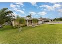Spacious home with lush green lawn, palm trees, and a solar panel roof at 220 Escambia Dr, Winter Haven, FL 33884