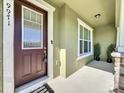 Inviting entryway featuring a stylish brown door, neutral colors, and elegant plants at 9971 Highland Sky Aly, Orlando, FL 32832
