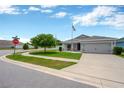 Corner lot featuring a gray home with an attached two-car garage and pristine landscaping at 305 St Georges Cir, Eagle Lake, FL 33839