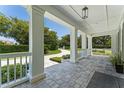 Inviting covered front porch with stone tile flooring and white columns at 5500 W Lake Butler Rd, Windermere, FL 34786