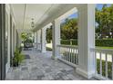 Relaxing covered front porch with hanging chair and stone tile flooring at 5500 W Lake Butler Rd, Windermere, FL 34786