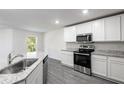 Modern kitchen boasts stainless appliances, granite counters, and sleek gray wood-look flooring at 567 Bay Leaf Dr, Poinciana, FL 34759