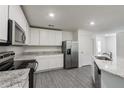 A bright kitchen features white cabinets, stainless steel appliances, and stylish gray wood-look flooring at 567 Bay Leaf Dr, Poinciana, FL 34759