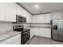 Well-lit kitchen featuring gray wood-look floors, stainless appliances, and granite countertops at 567 Bay Leaf Dr, Poinciana, FL 34759