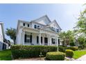 Charming two-story white house with a welcoming front porch, beautifully landscaped yard, and lush green bushes at 14563 Bahama Swallow Blvd, Winter Garden, FL 34787
