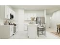 Bright, modern kitchen featuring white cabinetry, stainless steel appliances, and a functional island with seating at 7558 Headwaters Ct, Groveland, FL 34736