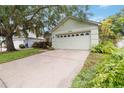 Single-story home featuring a wide driveway leading to a two-car garage, accented by lush greenery at 13219 Meadowlark Ln, Orlando, FL 32828