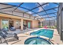Inviting screened-in pool area with a jacuzzi, lounge chairs, and covered patio seating, perfect for relaxation at 7634 Oakmoss Loop, Davenport, FL 33837