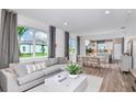 Open-concept living room with large windows, comfortable seating, and seamless flow to the kitchen and dining area at 8691 Sw 57Th Ln, Ocala, FL 34481