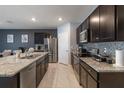 Stylish kitchen with granite countertops, stainless steel appliances, dark cabinetry and tile backsplash at 9532 Black Walnut Dr, Clermont, FL 34715