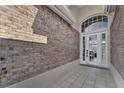 A close up front door with brick facade walls and tiled floor entry way at 1530 The Oaks Blvd, Kissimmee, FL 34746