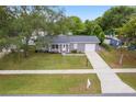 Aerial view of a cozy home with well-kept landscaping and a long driveway leading to an attached garage at 14464 Sw 34Th Terrace Rd, Ocala, FL 34473