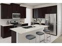 Modern kitchen featuring dark wood cabinets, stainless steel appliances, and a central island with stool seating at 2437 Spring Tune Aly, Kissimmee, FL 34744
